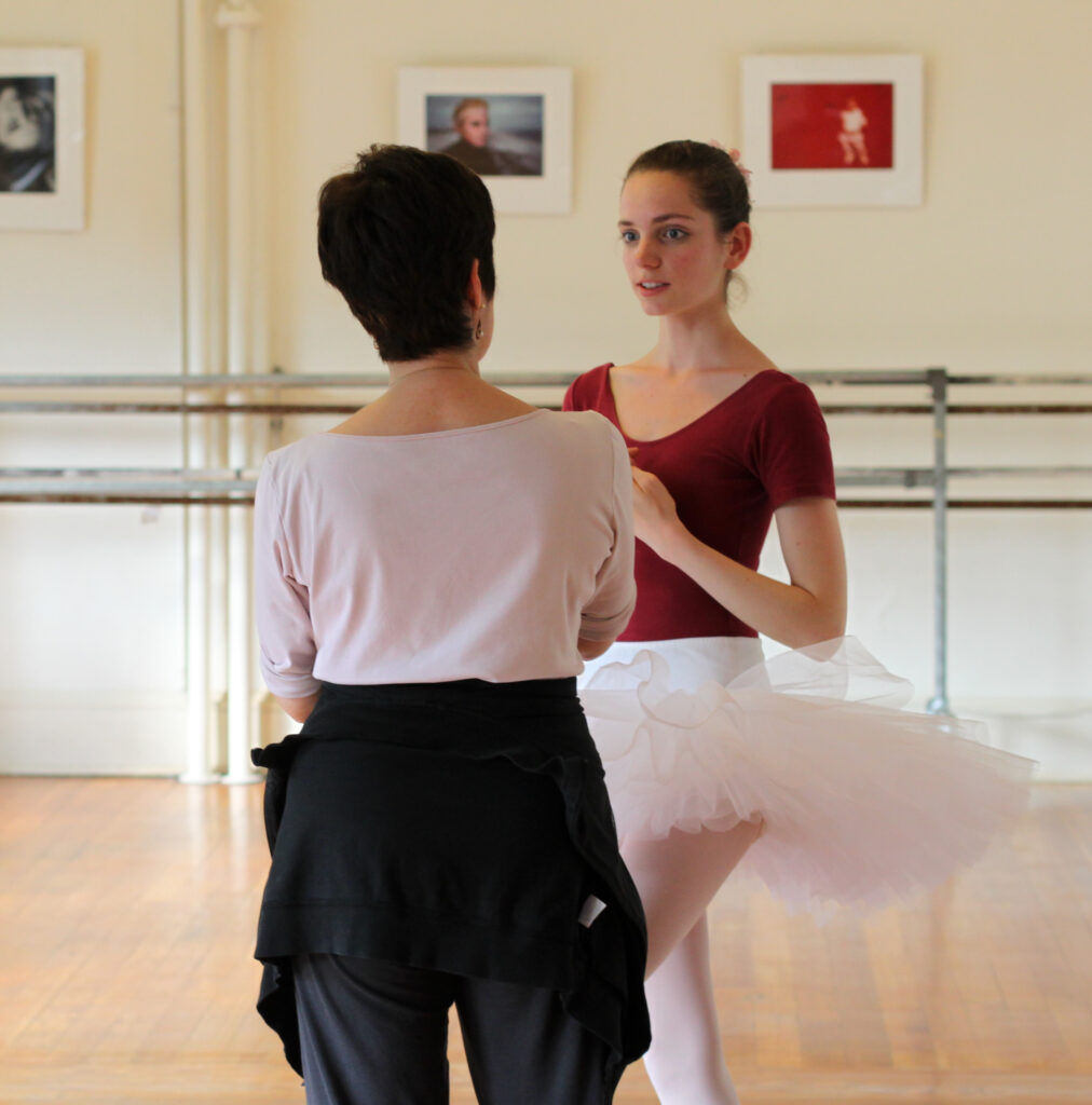 Paula K. Shiff instructs a female ballet dancer in a tutu.