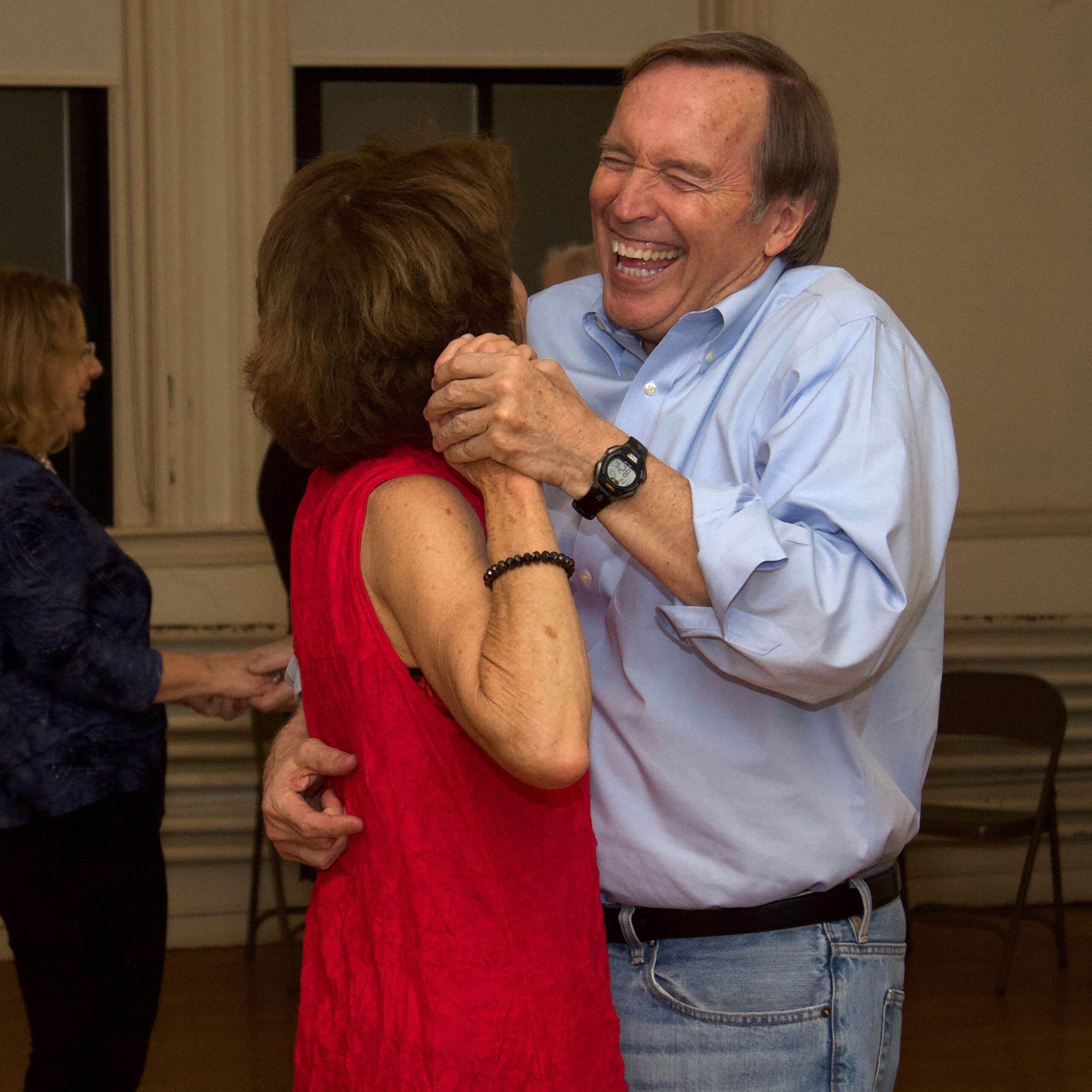 A man and woman laugh as they dancer together.