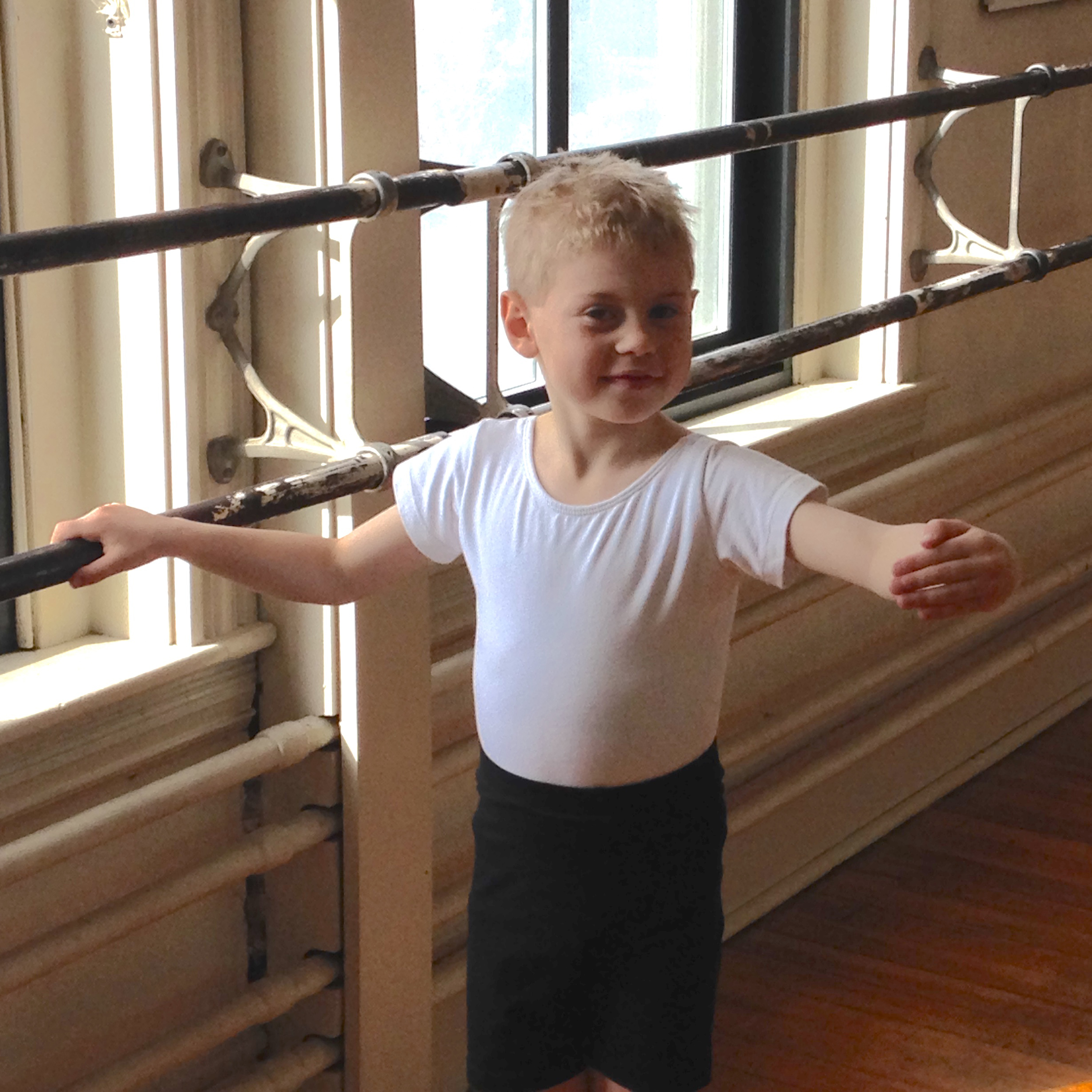 Little boy doing ballet at the barre