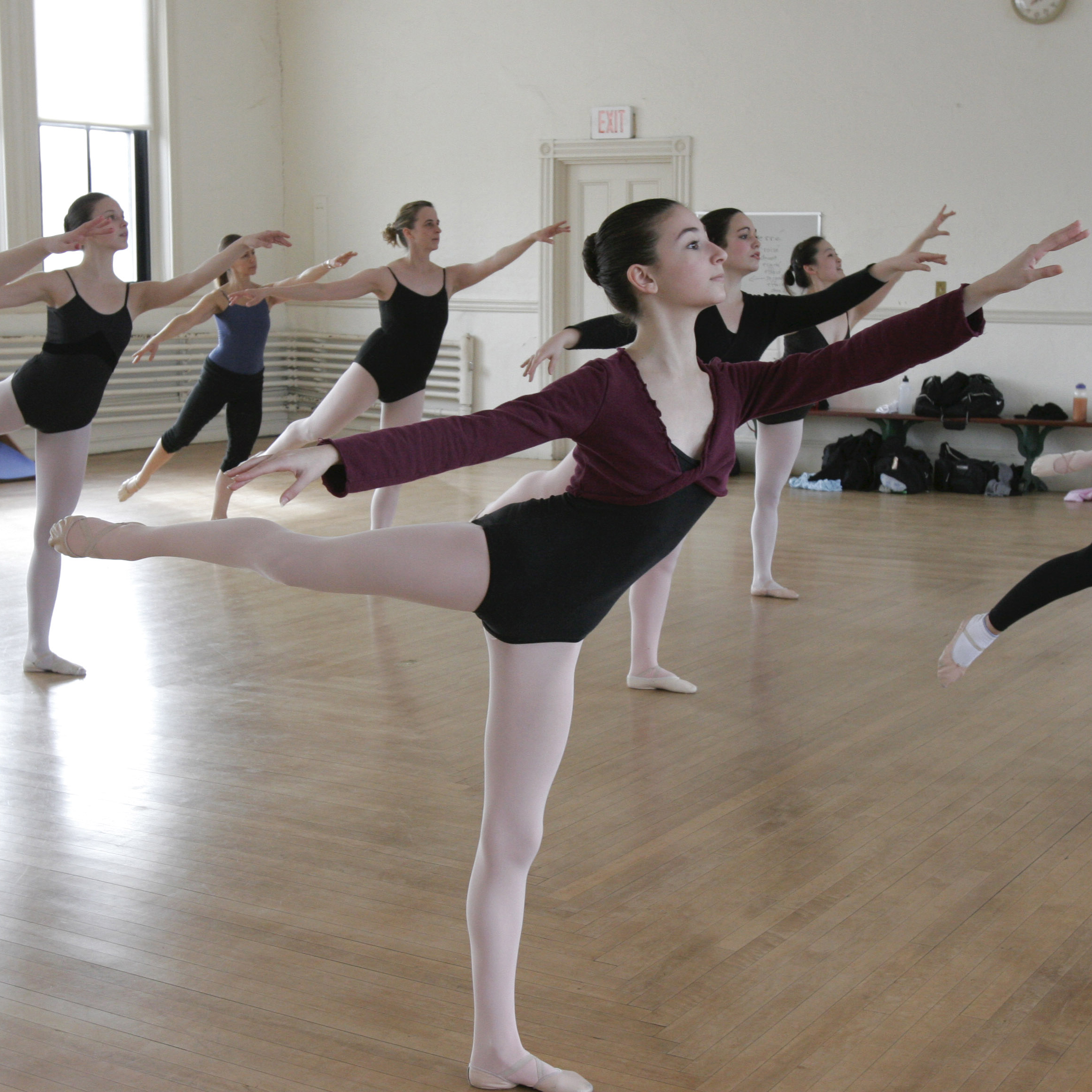 Dance studio full of ballet students pose in Arabesque.